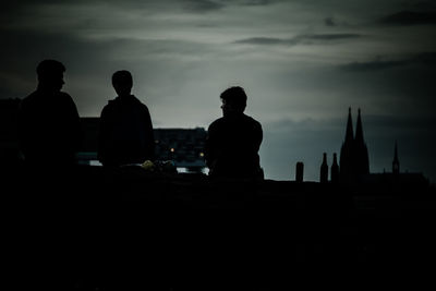 Silhouette people sitting against sky during sunset