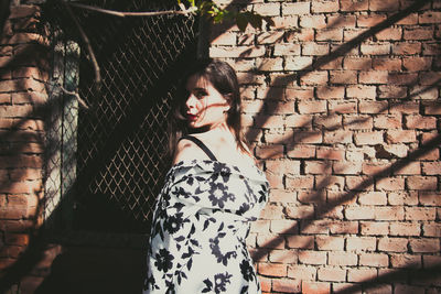 Portrait of woman standing by wall