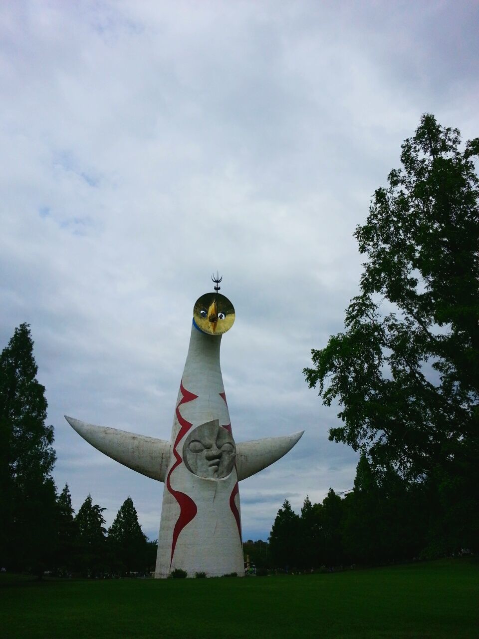 tree, sky, low angle view, cloud - sky, human representation, sculpture, cloud, grass, cloudy, flag, art, statue, art and craft, patriotism, outdoors, day, creativity, religion, growth