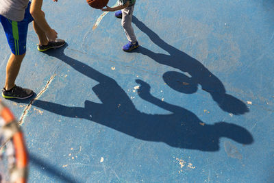 Man playing basketball with son at sports court