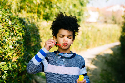 Cute boy blowing bubble on footpath