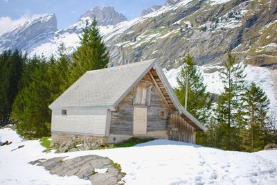 House by mountains against sky during winter