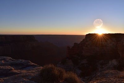 Scenic view of red rocks and canyon against clear sky during sunset