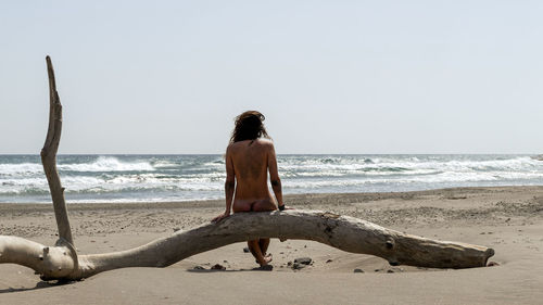 Rear view of woman on beach against clear sky