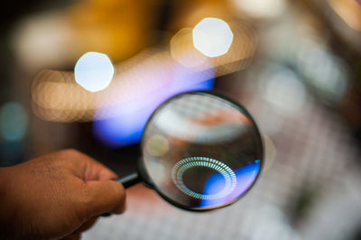 Man holding magnifying glass in front of glowing circle