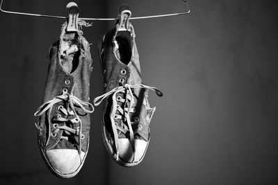 Close-up of weathered shoes hanging on rope against wall