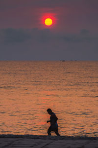 Man on beach against sky during sunset