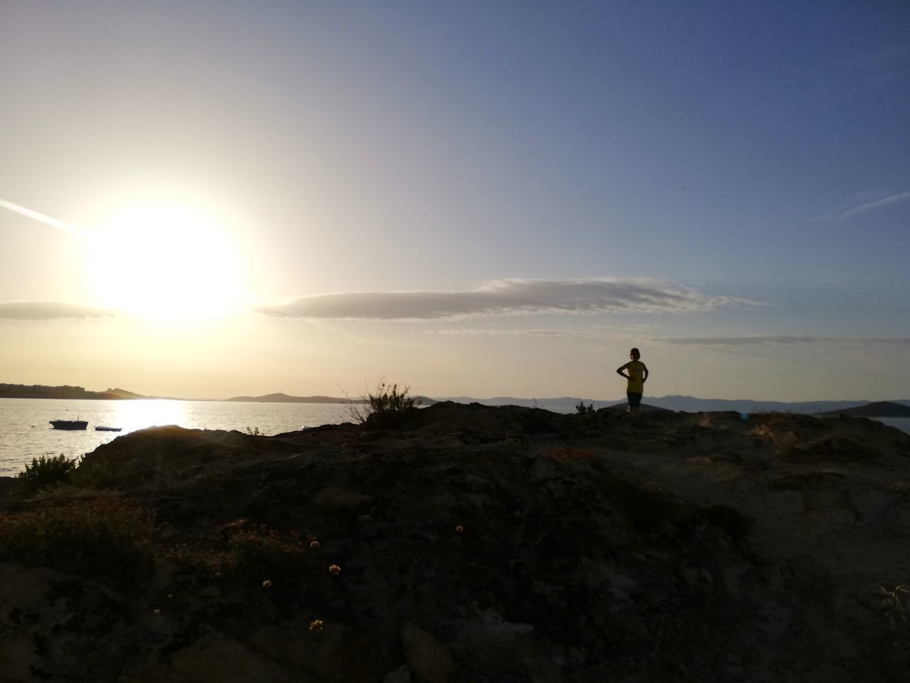 sky, beauty in nature, one person, scenics - nature, sunset, real people, land, tranquility, silhouette, tranquil scene, leisure activity, nature, sea, water, beach, standing, lifestyles, sun, non-urban scene, outdoors