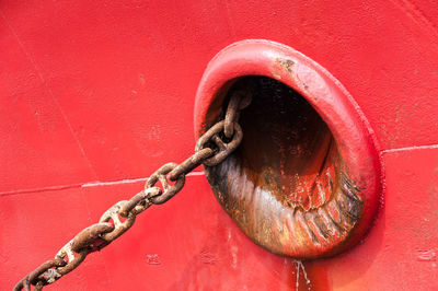 Close-up of rusty chain of red fishing boat