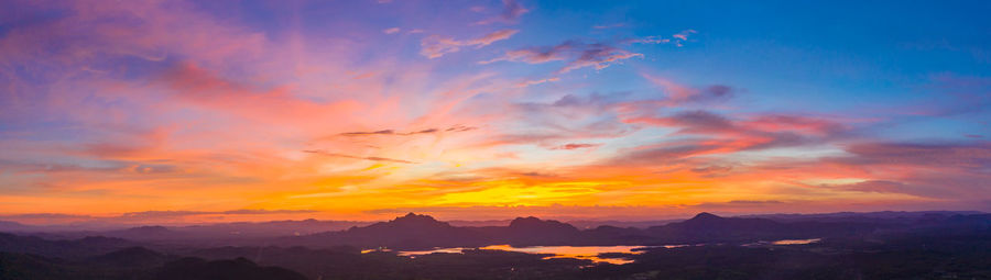 Scenic view of dramatic sky over silhouette landscape during sunset