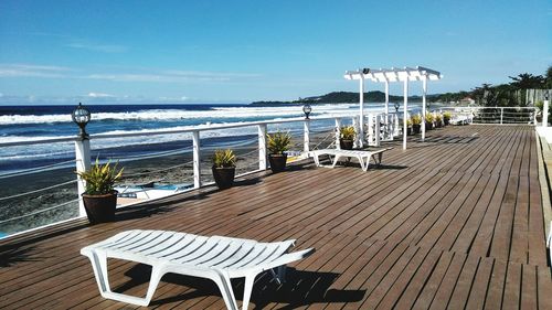 Chairs and table at beach against sky