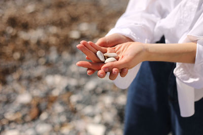 Midsection of woman holding pebbles outdoors