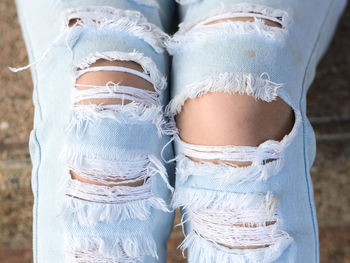 Cropped image of woman wearing torn jeans on steps