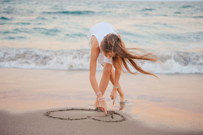 Full length of young woman standing at beach