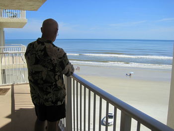 Rear view of man looking at sea against sky