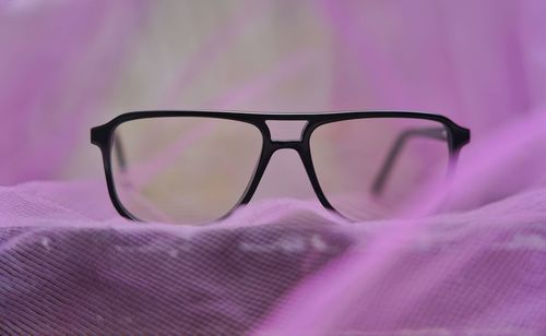 Close-up of sunglasses on pink glass