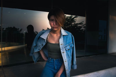 Portrait of young woman standing against built structure