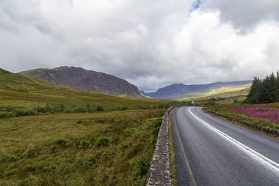 Empty road along landscape and mountains against sky