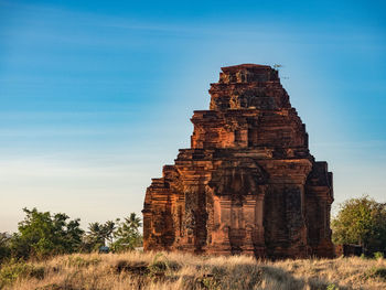 Old ruin building on field against blue sky