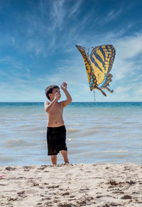 Little boy flies a butterfly kite on the shores of lake michigan in the usa
