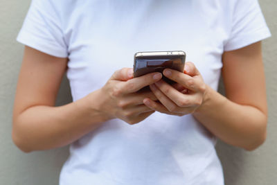 Midsection of woman using phone against wall