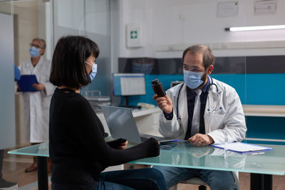 Doctor wearing mask showing medicine to patient