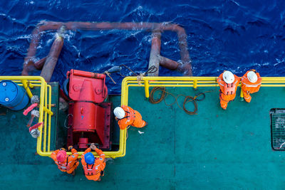 High angle view of workers standing on boat in sea