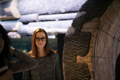 Portrait of smiling young woman standing in aquarium 