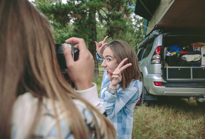 Woman photographing friend through camera in camp