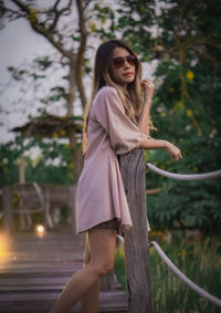 Young woman standing against trees