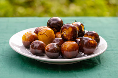 Fresh cherry tomatoes of different varieties on a plate on the blurred background, close-up