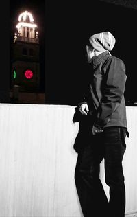 Man photographing woman standing on street at night