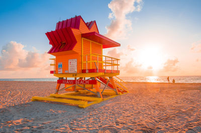 Lifeguard hut on beach against sky during sunset