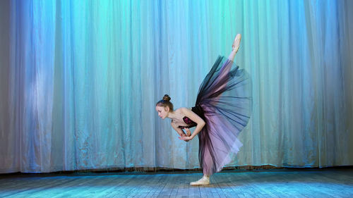 Ballet rehearsal, on the stage of the old theater hall. young ballerina in lilac black dress