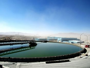 Scenic view of river in front of mountains against clear blue sky