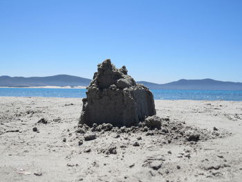 Sandcastle on shore at beach against sky