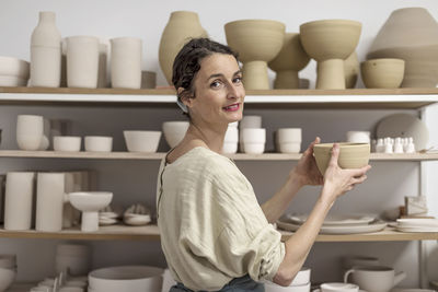 Portrait of young woman sitting in shelf