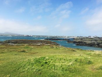 Scenic view of sea and green landscape against sky