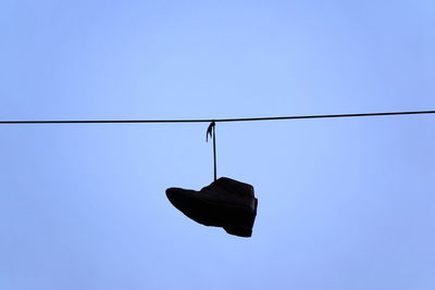 Low angle view of shoes against clear blue sky