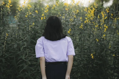 Rear view of woman standing against plants