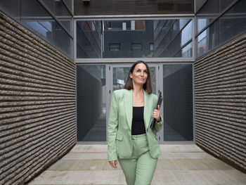 Portrait of young woman standing against building