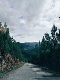 Empty road leading towards mountains against sky