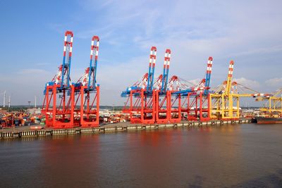 Cranes at harbor against blue sky