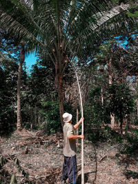 Side view of senior man holding bamboo while standing in forest