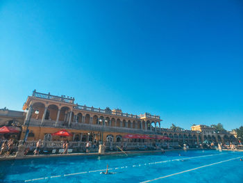 View of swimming pool in city against clear blue sky