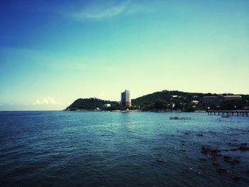 Scenic view of sea by buildings against clear blue sky