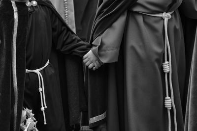 Midsection of friends wearing religious dress while holding hands during easter