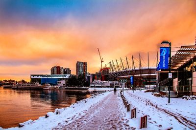 Snow covered cityscape against sky during sunset