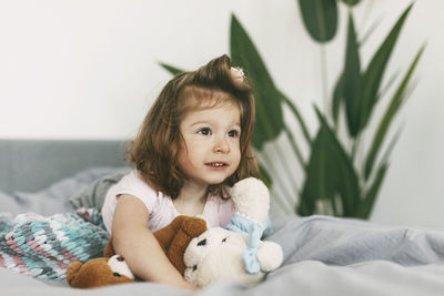 Portrait of a charming little girl lying on a bed with her teddy bear