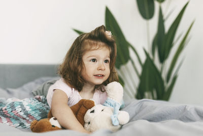 Portrait of cute baby girl lying on bed at home